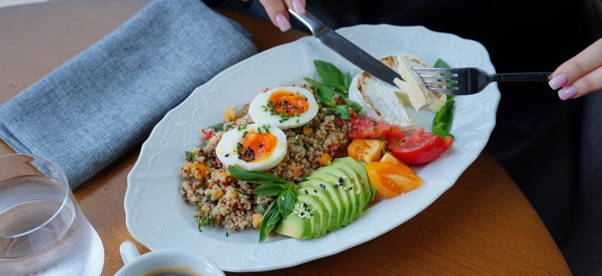 A delicious and healthy breakfast featuring avocado, eggs, and coffee served on a wooden table.