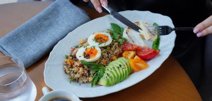 A delicious and healthy breakfast featuring avocado, eggs, and coffee served on a wooden table.